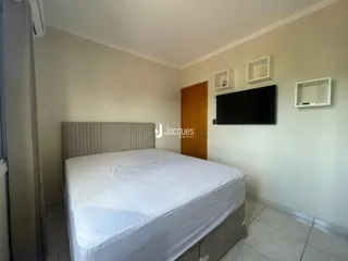Quarto com cama e televisão montada na parede.