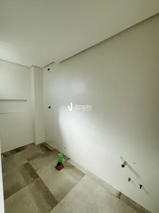Interior de um ambiente com paredes brancas e piso de cerâmica.