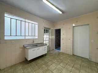 Vista interna de uma cozinha com piso de cerâmica e janela com grades.