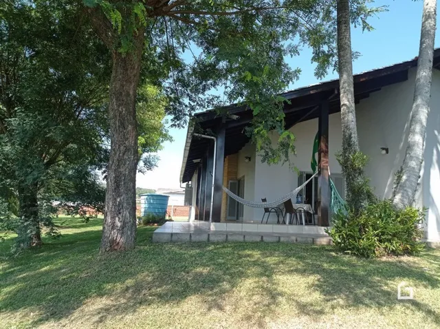 Fachada de uma residência em Lajeado, Brasil, com gramado e árvores ao redor.