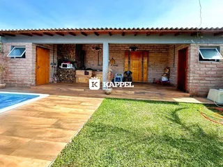 Foto da fachada de uma casa com piscina e jardim.