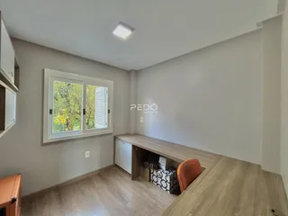 Ambiente interno de uma sala com piso de madeira e janela.