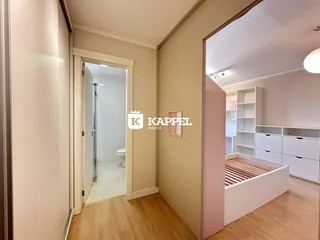 Hall de entrada com piso de madeira e acesso a um banheiro moderno.