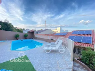 Vista de uma piscina externa com deck e telhado com painéis solares.