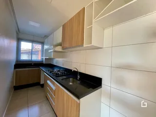 Vista interna de uma cozinha com armários de madeira e bancada escura.