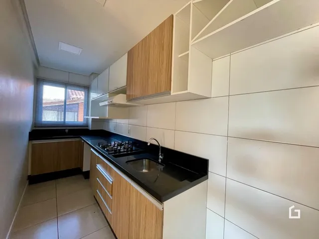Vista interna de uma cozinha com armários de madeira e bancada escura.