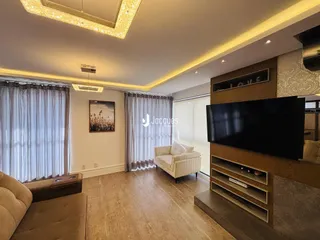 Sala de estar com piso de madeira e televisão montada na parede.