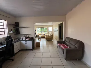 Interior de uma sala de estar com piso de cerâmica clara e ambiente aberto.