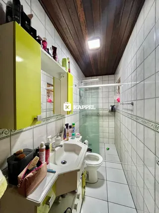 Foto de um banheiro com revestimento de azulejos brancos e bancada clara.