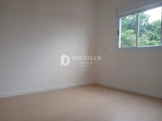 Ambiente interno de uma sala com piso de madeira e janela.