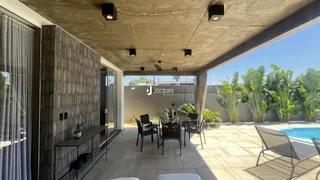 Área externa com mobiliário de lazer e vista para o jardim e piscina.