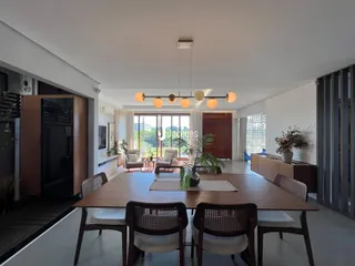 Ambiente de jantar amplo com mesa de madeira e decoração moderna.