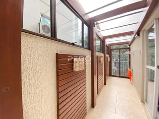 Foto de um corredor com grandes janelas e detalhes em madeira em uma residência.