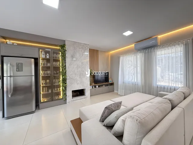 Sala de estar moderna com lareira e grandes janelas em um imóvel no Brasil.