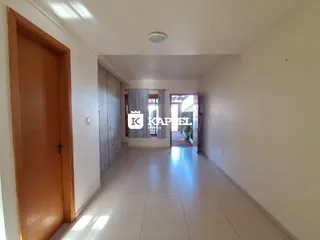 Hall de entrada com piso claro e porta de madeira em um imóvel.