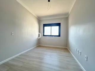 Ambiente interno de uma sala com piso de madeira clara e parede branca.