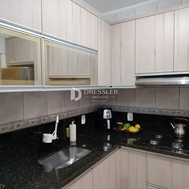 Foto de uma cozinha moderna com armários brancos e bancada escura.