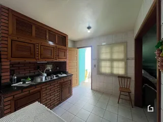 Vista da cozinha com armários de madeira e revestimento de tijolos.