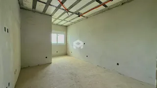 Foto de um cômodo interno com paredes brancas e teto exposto.