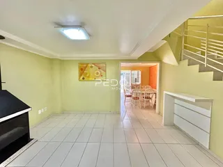Sala de estar com paredes verdes e piso de cerâmica branca.