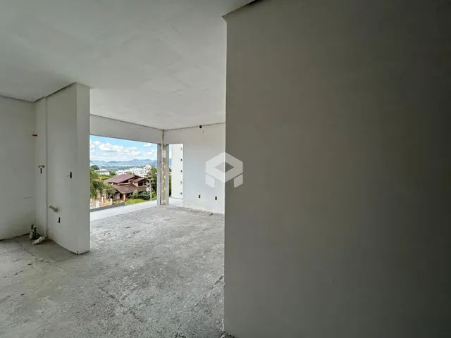 Vista interna de um espaço com paredes brancas e piso de concreto aparente.