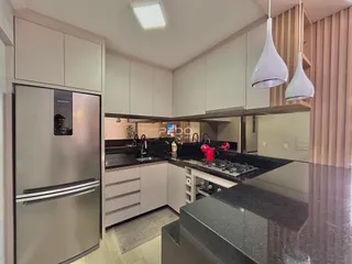 Cozinha moderna com armários brancos e bancada escura.