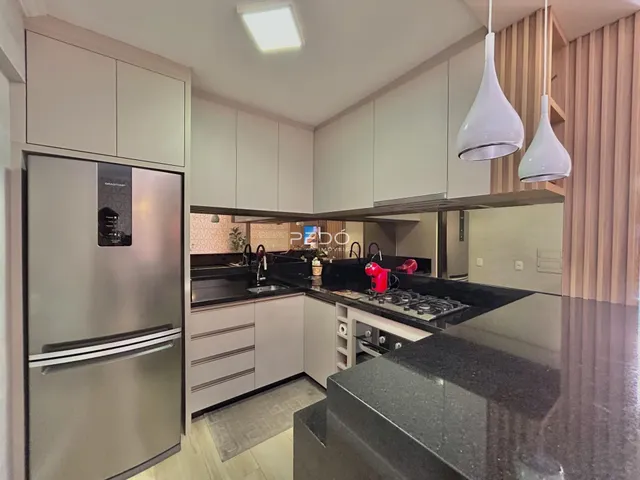 Cozinha moderna com armários brancos e bancada escura.