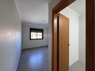 Vista de um corredor interno com paredes brancas e piso claro.
