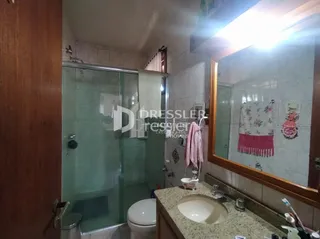 Foto de um banheiro com box de vidro e azulejos brancos.