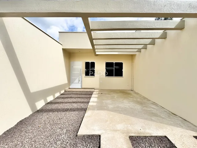 Vista externa de uma residência com fachada clara e piso de cascalho.