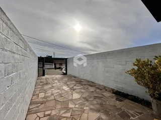 Área externa pavimentada com pedras entre duas paredes de concreto.