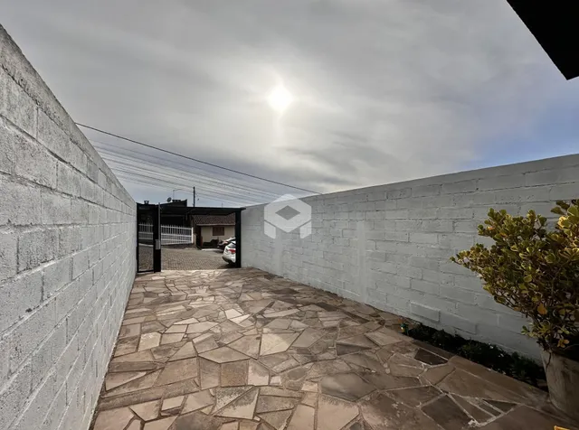 Área externa pavimentada com pedras entre duas paredes de concreto.