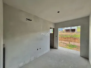 Interior de um espaço com paredes brancas e piso de concreto.