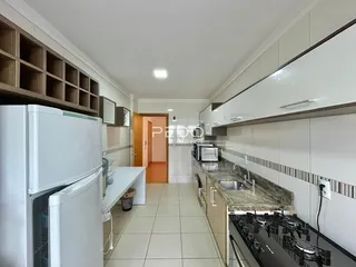 Cozinha com armários brancos e piso de cerâmica clara.