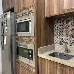 Cozinha com armários de madeira e eletrodomésticos em aço inoxidável.