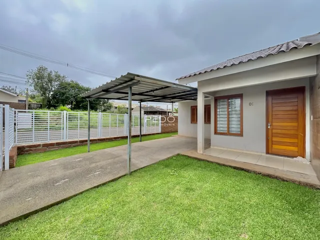 Fachada da casa com cerca branca e gramado na frente.
