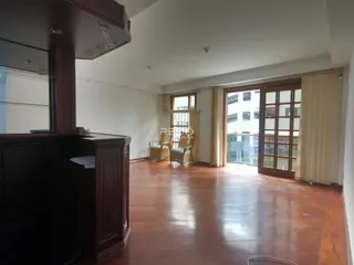 Interior de uma sala de estar com piso de madeira e portas de vidro.