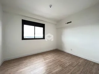 Ambiente interno de uma sala com piso de madeira clara e janela.
