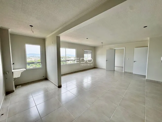 Ambiente interno de uma sala ampla com piso de cerâmica clara e janelas.