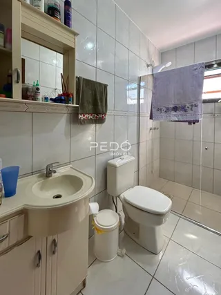 Foto de um banheiro com revestimento cerâmico e louças sanitárias brancas.