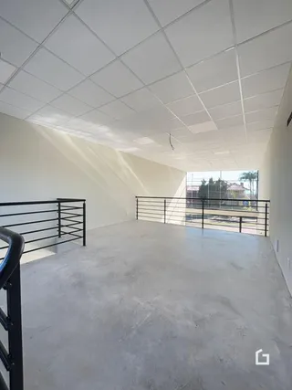 Espaço interno com piso de concreto e teto de gesso branco.