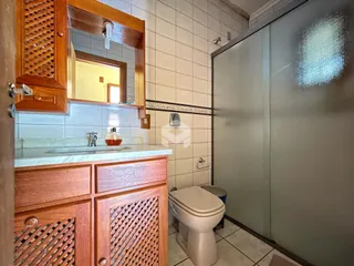 Foto de um banheiro com bancada de madeira e box de vidro.