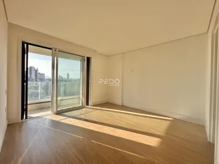 A sala de estar apresenta piso de madeira e grandes portas de vidro com vista para a paisagem.