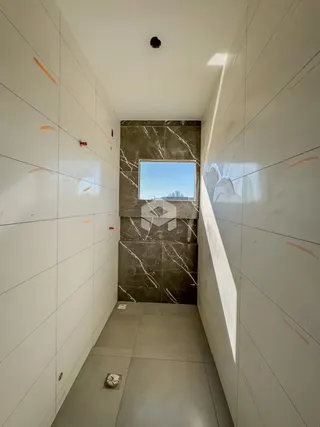 Corredor interno com paredes brancas e piso de cerâmica.