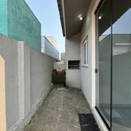 Corredor externo de concreto entre duas estruturas em uma residência.