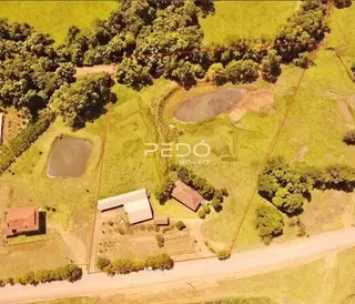 Vista aérea de uma propriedade rural com áreas verdes e corpos d'água.