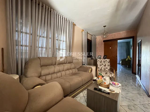 Uma sala de estar com um sofá grande e cortinas claras.
