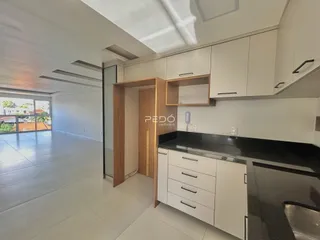 Vista da cozinha moderna com armários brancos e bancadas escuras.