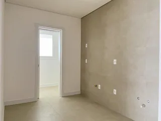 Foto de um corredor interno com paredes claras e porta branca.