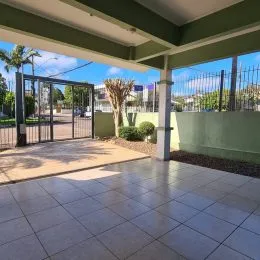 Área externa pavimentada com piso de cerâmica sob uma estrutura coberta.